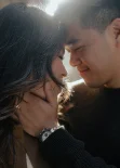 Couple shares an intimate moment, smiling softly during a Vacation Portraits photoshoot in natural sunlight.