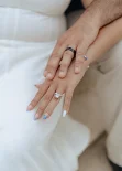 Engaged couple’s hands gently intertwined, showing off rings during a couples & engagements photoshoot.