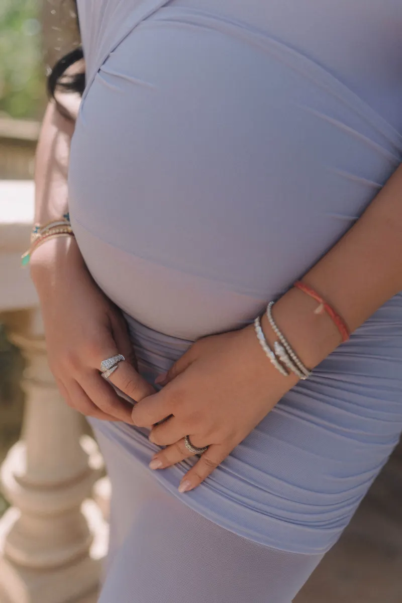 Expectant mother in a lavender dress cradles her belly, captured during a vacation portraits photoshoot.