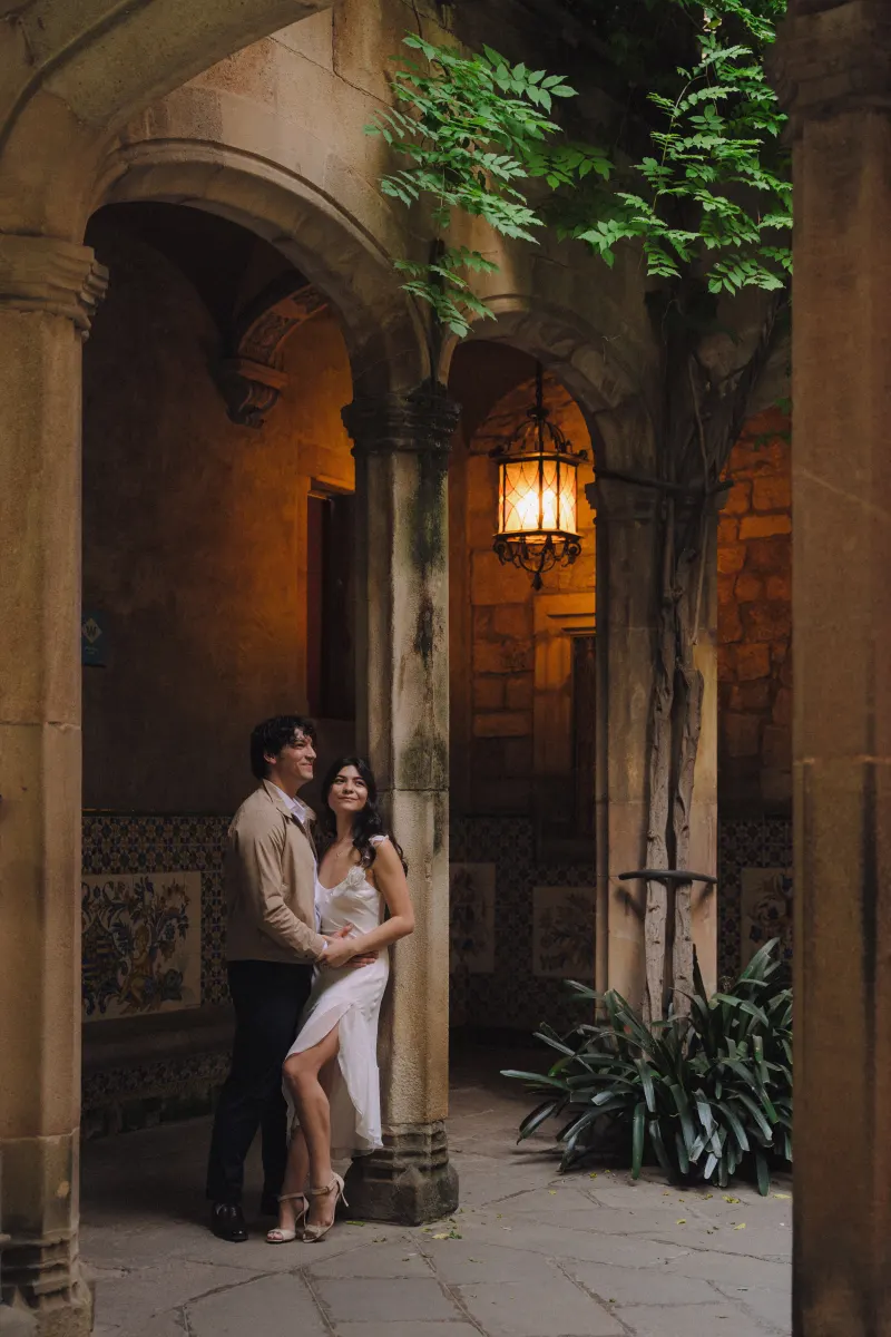 Joyful couple embraces under stone arches during an engagement photoshoot in a romantic, historic courtyard.