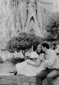 Joyful couple laughing together during an engagement photoshoot in front of Sagrada Familia, Barcelona.