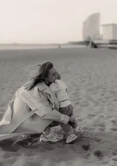 Mother hugging baby on Barcelona beach during family photoshoot